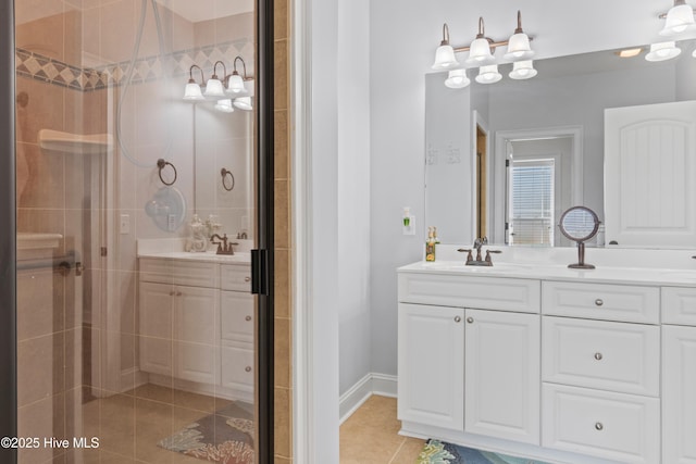 bathroom with tile patterned flooring, tiled shower, vanity, and baseboards