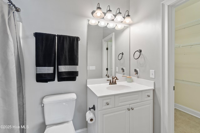 bathroom with toilet, a walk in closet, and vanity