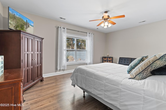 bedroom featuring a ceiling fan, baseboards, visible vents, and wood finished floors