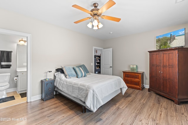 bedroom featuring ceiling fan, baseboards, wood finished floors, and ensuite bathroom