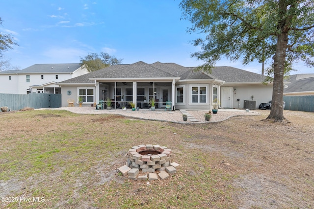 rear view of house with a fire pit, central AC, fence, a sunroom, and a yard