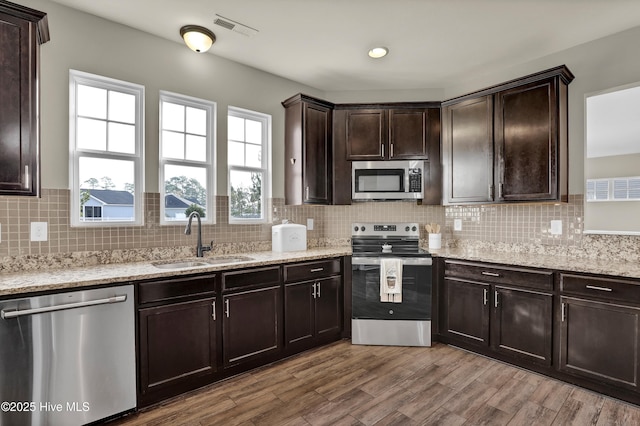 kitchen featuring visible vents, wood finished floors, stainless steel appliances, dark brown cabinets, and a sink