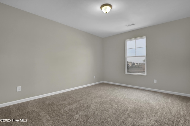 carpeted spare room featuring baseboards and visible vents