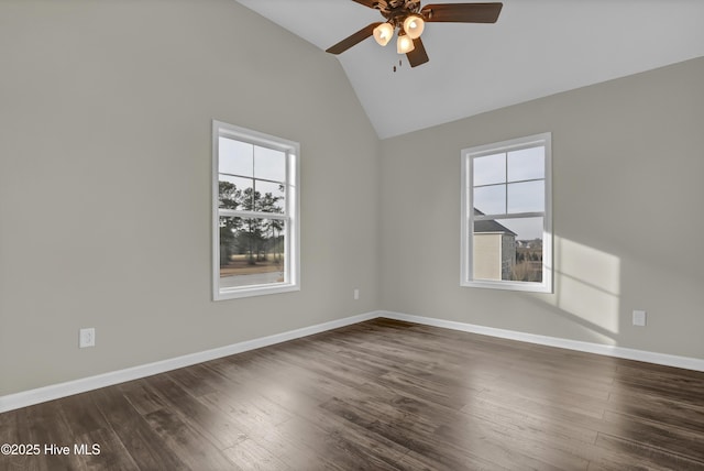 spare room featuring dark wood-type flooring, vaulted ceiling, baseboards, and a ceiling fan