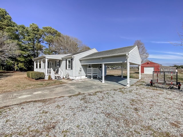 view of front of house featuring covered porch, gravel driveway, and an outdoor structure