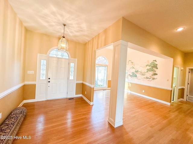 foyer with a notable chandelier, baseboards, and light wood-style floors