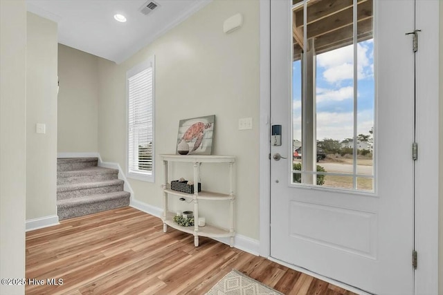 foyer featuring baseboards, stairs, visible vents, and wood finished floors