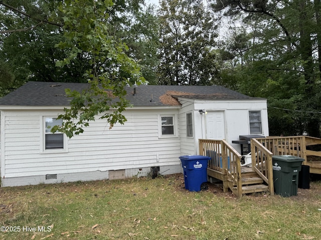 rear view of house with crawl space, a shingled roof, a deck, and a lawn