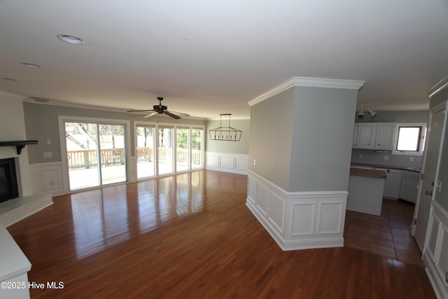 unfurnished living room featuring ornamental molding, a fireplace, dark wood finished floors, and a healthy amount of sunlight