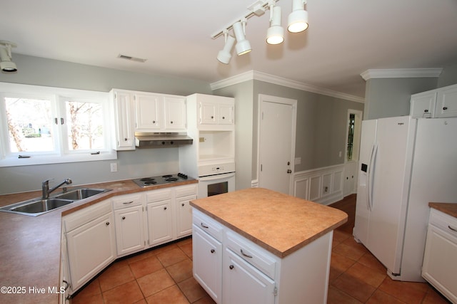 kitchen with under cabinet range hood, white appliances, a kitchen island, a sink, and white cabinets