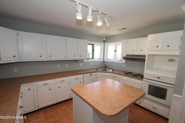 kitchen with white appliances, tile patterned flooring, under cabinet range hood, white cabinetry, and a sink