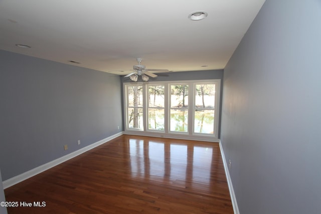 unfurnished room featuring ceiling fan, wood finished floors, and baseboards