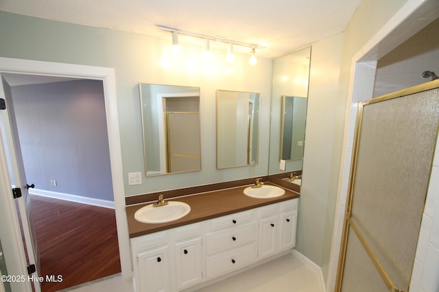 full bathroom with double vanity, baseboards, and a sink