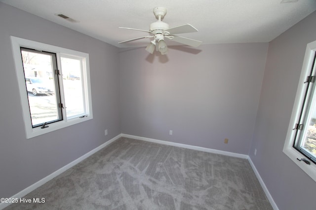 spare room with visible vents, ceiling fan, light carpet, and baseboards