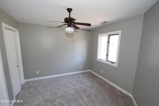 carpeted spare room featuring ceiling fan, visible vents, and baseboards