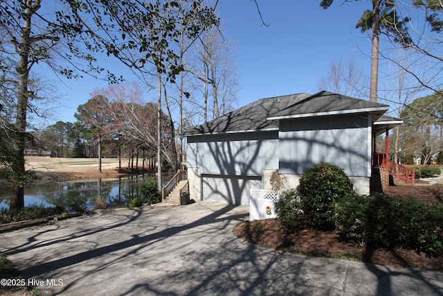 view of home's exterior with a garage, a water view, and driveway