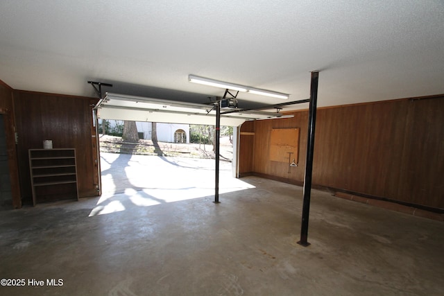 garage with a garage door opener and wood walls