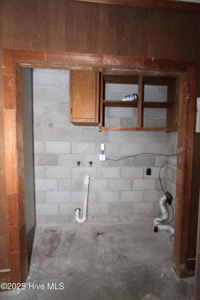 clothes washing area featuring concrete block wall