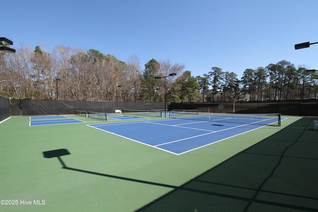 view of tennis court with community basketball court and fence