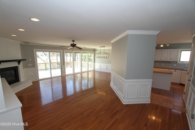 unfurnished living room featuring a brick fireplace, plenty of natural light, and wood finished floors