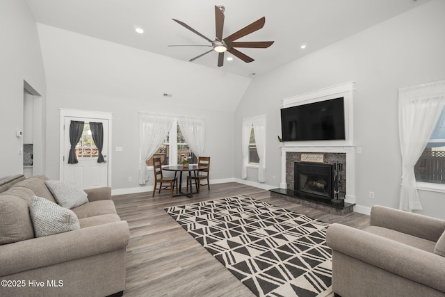 living room with recessed lighting, a premium fireplace, baseboards, and wood finished floors