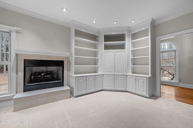 unfurnished living room featuring crown molding, recessed lighting, a premium fireplace, light carpet, and baseboards