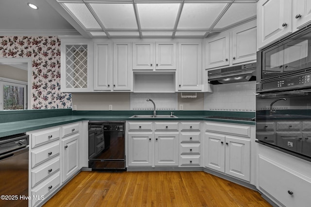 kitchen featuring black appliances, under cabinet range hood, white cabinetry, and a sink