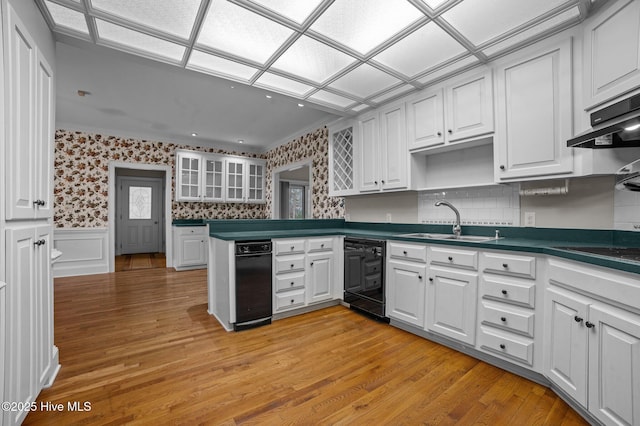 kitchen with wallpapered walls, white cabinets, dark countertops, glass insert cabinets, and a sink