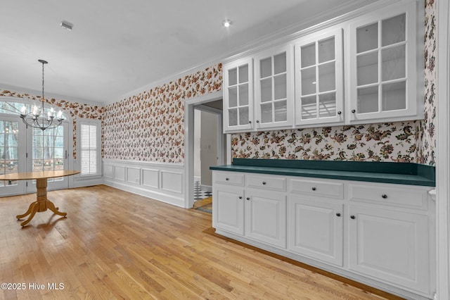 kitchen featuring a wainscoted wall, dark countertops, glass insert cabinets, white cabinetry, and wallpapered walls