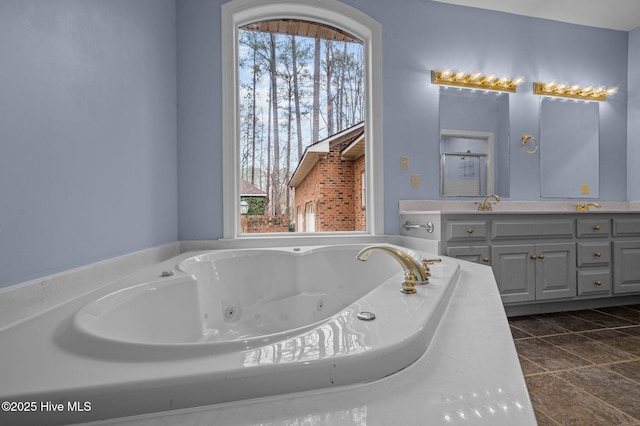 bathroom with a whirlpool tub, vanity, and a healthy amount of sunlight