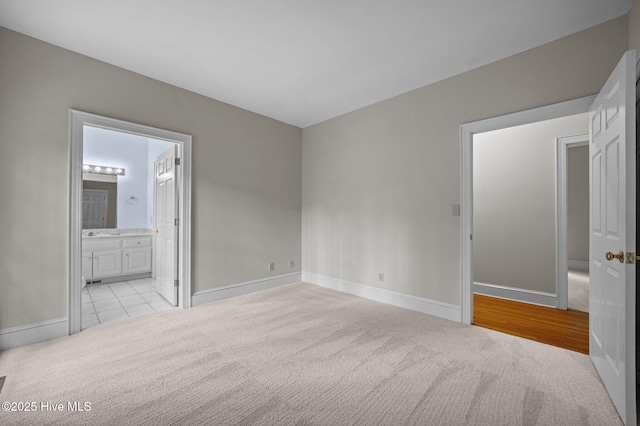 unfurnished bedroom with light carpet, connected bathroom, and baseboards