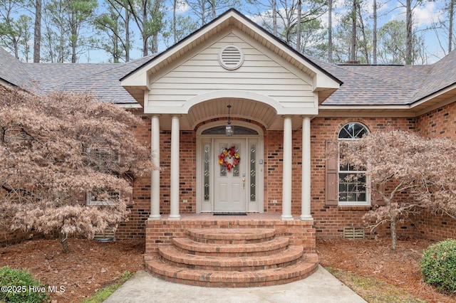 property entrance featuring a porch, crawl space, brick siding, and roof with shingles