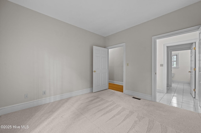 unfurnished bedroom featuring light carpet, visible vents, and baseboards