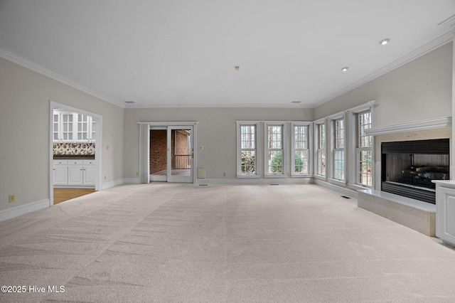 unfurnished living room featuring light carpet, baseboards, a fireplace with raised hearth, and ornamental molding