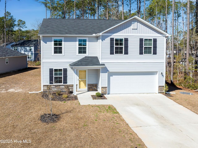 view of front of property with a garage, driveway, stone siding, board and batten siding, and a front yard