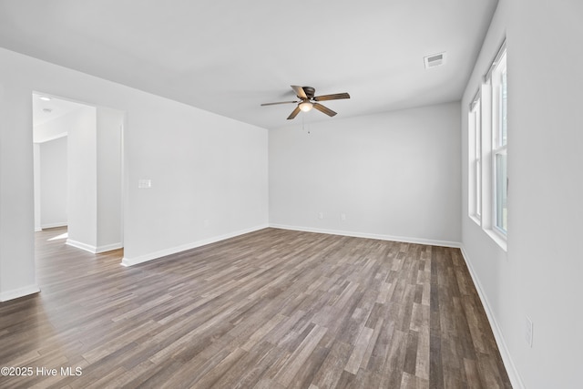 empty room featuring baseboards, visible vents, ceiling fan, and wood finished floors