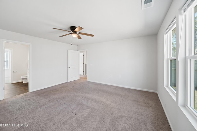 carpeted empty room featuring baseboards, visible vents, and ceiling fan