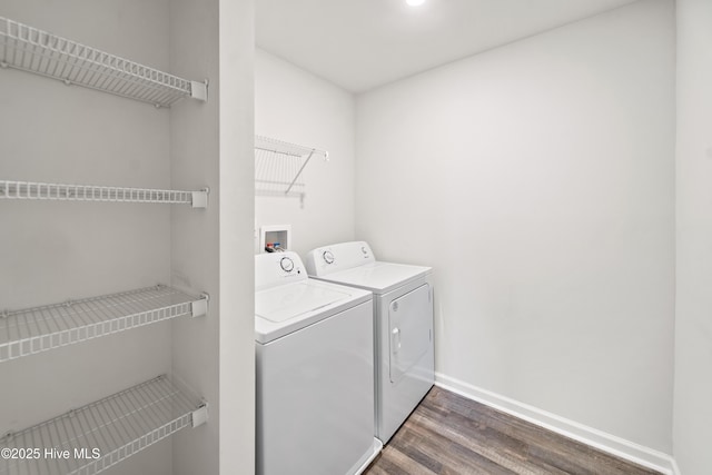 washroom featuring laundry area, dark wood-type flooring, separate washer and dryer, and baseboards