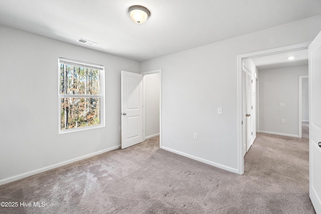 unfurnished bedroom with visible vents, light carpet, and baseboards