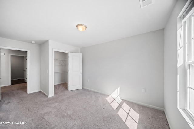 unfurnished bedroom featuring light carpet, baseboards, multiple windows, and visible vents