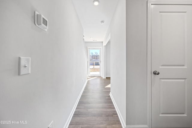 hallway featuring dark wood-style flooring and baseboards