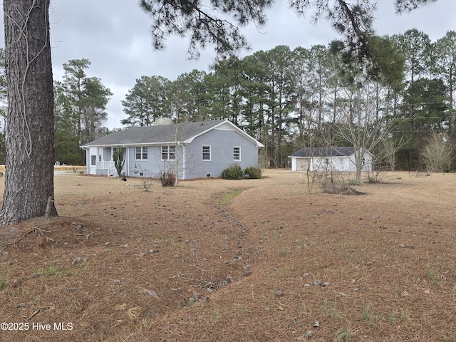 rear view of property with crawl space and a detached garage