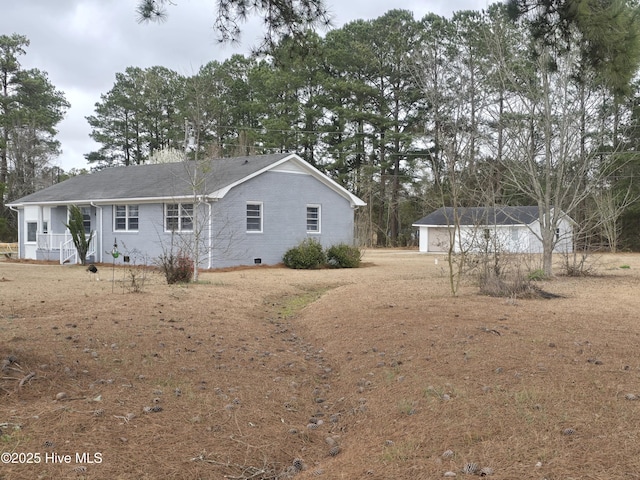 rear view of property with crawl space and a detached garage