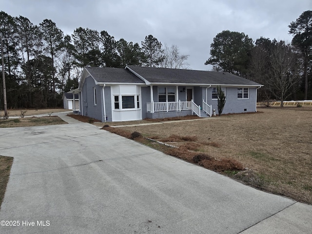 ranch-style house featuring covered porch, a front lawn, an outbuilding, and brick siding