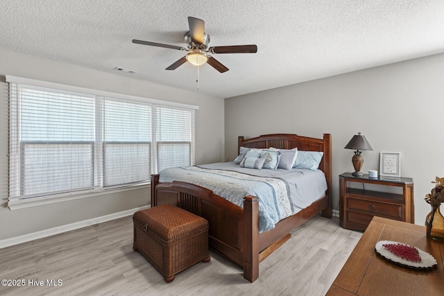 bedroom with baseboards, ceiling fan, light wood-style flooring, and a textured ceiling