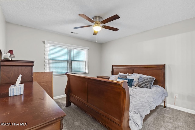 bedroom featuring a textured ceiling, ceiling fan, visible vents, baseboards, and dark colored carpet