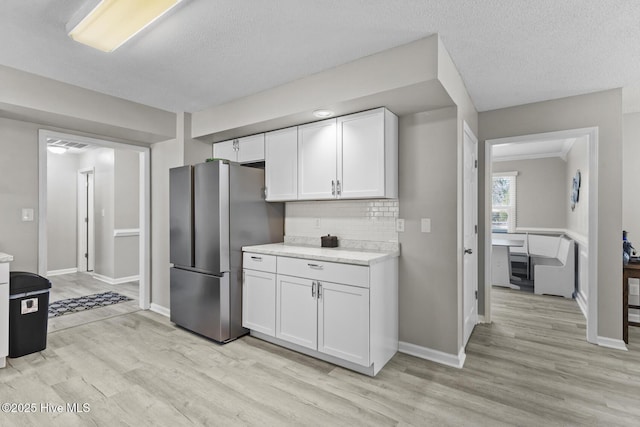 kitchen with light countertops, light wood finished floors, freestanding refrigerator, and white cabinetry