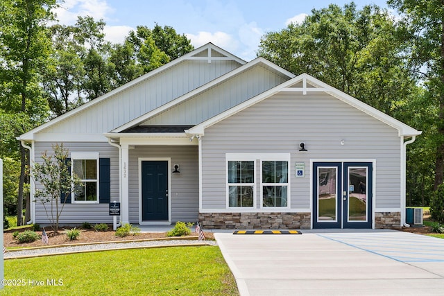 craftsman inspired home with cooling unit, stone siding, and a front yard