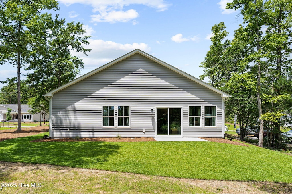 rear view of house with a lawn and a patio