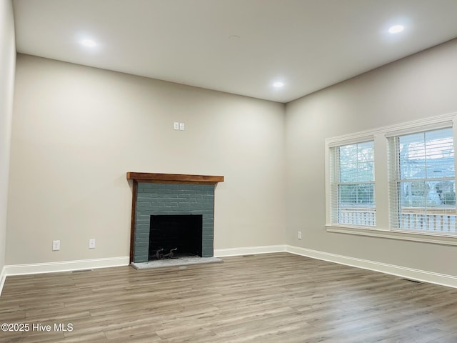 unfurnished living room with recessed lighting, a fireplace, wood finished floors, and baseboards